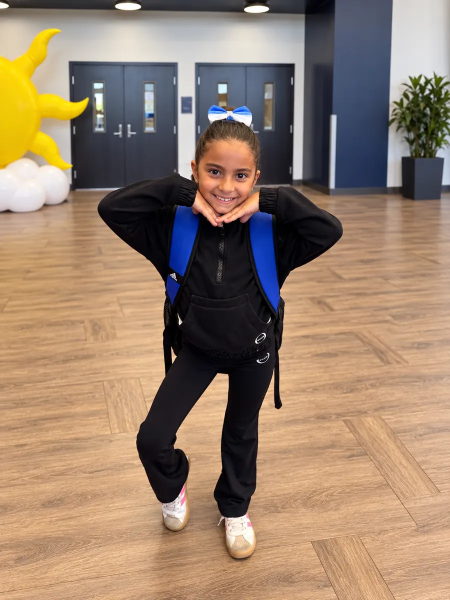 Amelia Kyres smiling with her hands under her chin and a blue gymnastics bow.