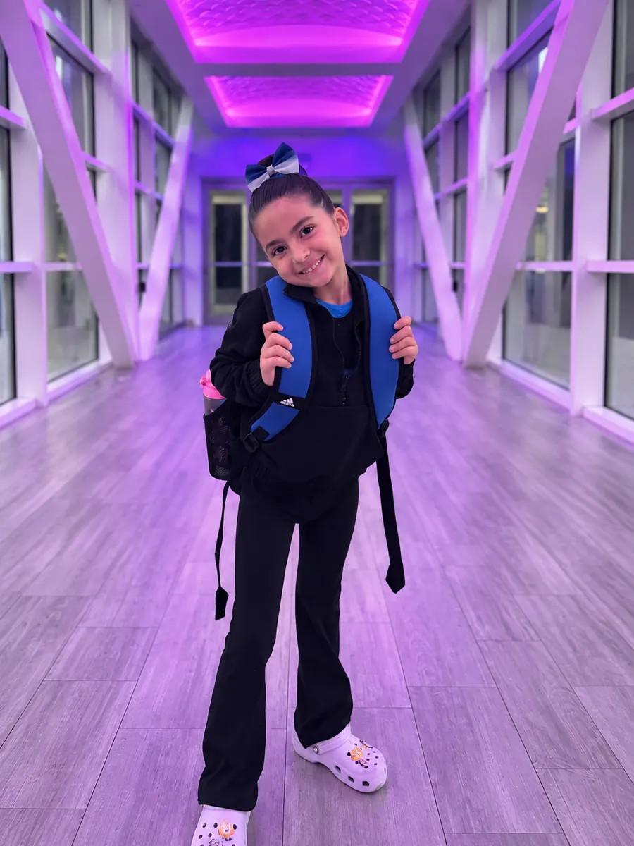 Amelia Kyres smiling in a purple-lit hallway before gymnastics.